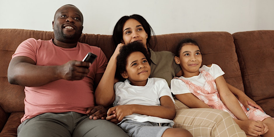 Family sitting on a couch watching television.
